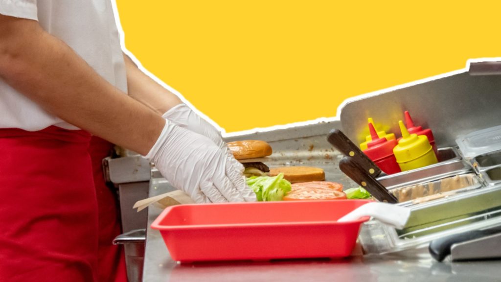 A fast food worker preparing burgers.